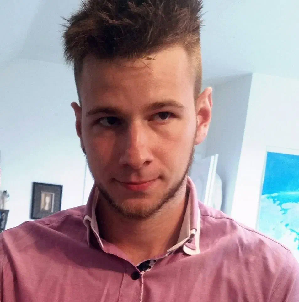 Richie, our Tron manager – portrait of a young man with spiky hair in a pink shirt