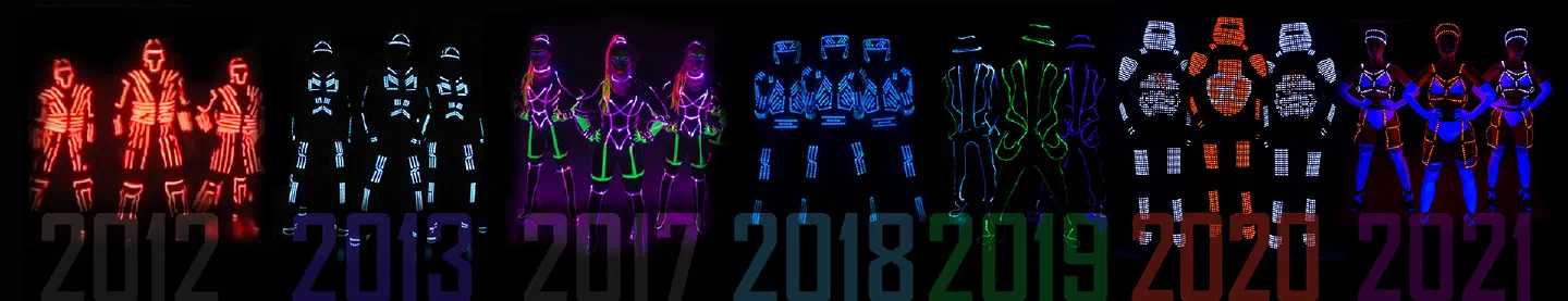 Timeline of our LED costumes from 2012 to 2021 – groups of dancers in glowing red, blue, purple, green and orange LED suits above the years 2012, 2013, 2017, 2018, 2019, 2020 and 2021