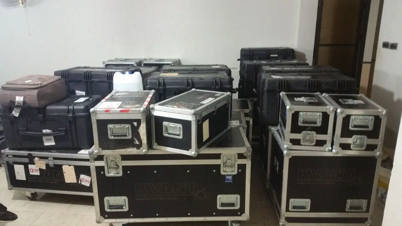 Our laser equipment packed for the trip – stacks of black KVANT flight cases and protective cases in a room