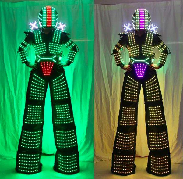 The same LED robot on stilts shown twice – its suit, long extended legs and helmet covered in rows of LED pixels, glowing green on the left and warm white with a purple helmet stripe on the right