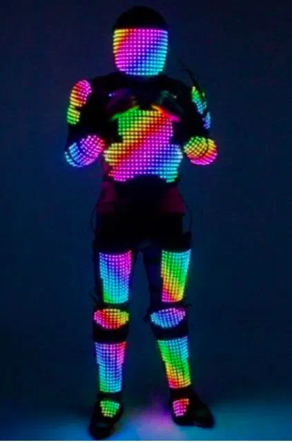 LED digital suit – a performer in a suit covered with pixel LED panels glowing in rainbow colours on the helmet, chest, arms and legs