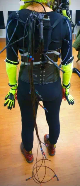 Back of a dancer wearing the receiver harness, with the unplugged cables of the spiral cord, each of a different length, hanging down to the floor