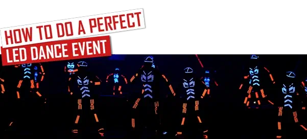 How to do a perfect LED dance event – red and white banners above Tron dancers in glowing blue and orange LED suits on a dark stage