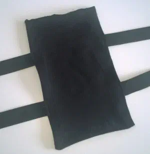 Black fabric LED Suit Receiver backpack with two elastic straps, lying on a white table