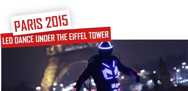 Paris 2015 – LED dance under the Eiffel Tower – a dancer in a glowing blue LED suit and helmet at night, with the lit Eiffel Tower in the background