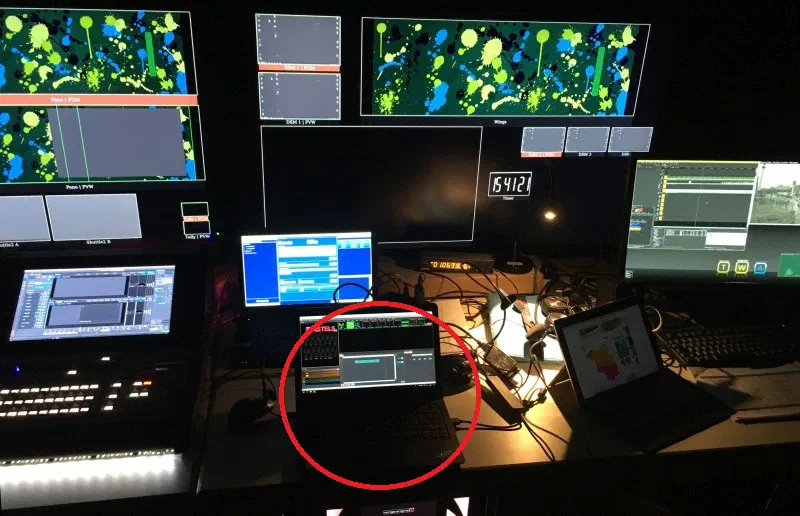 Control room full of video monitors and a video control desk – a red circle marks the small laptop with LED Strip Studio in the middle