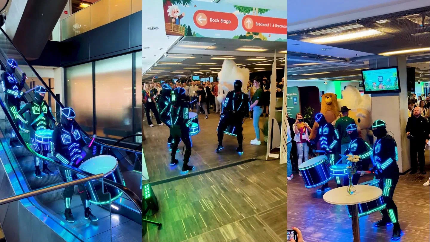 Three shots of the Tron Drummers walking act at a conference – drummers in LED suits with glowing drums coming down an escalator, playing among the guests and next to a mascot