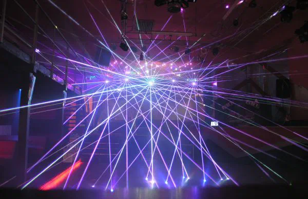 Fans of purple and white laser beams spreading from a stage across an empty club dance floor