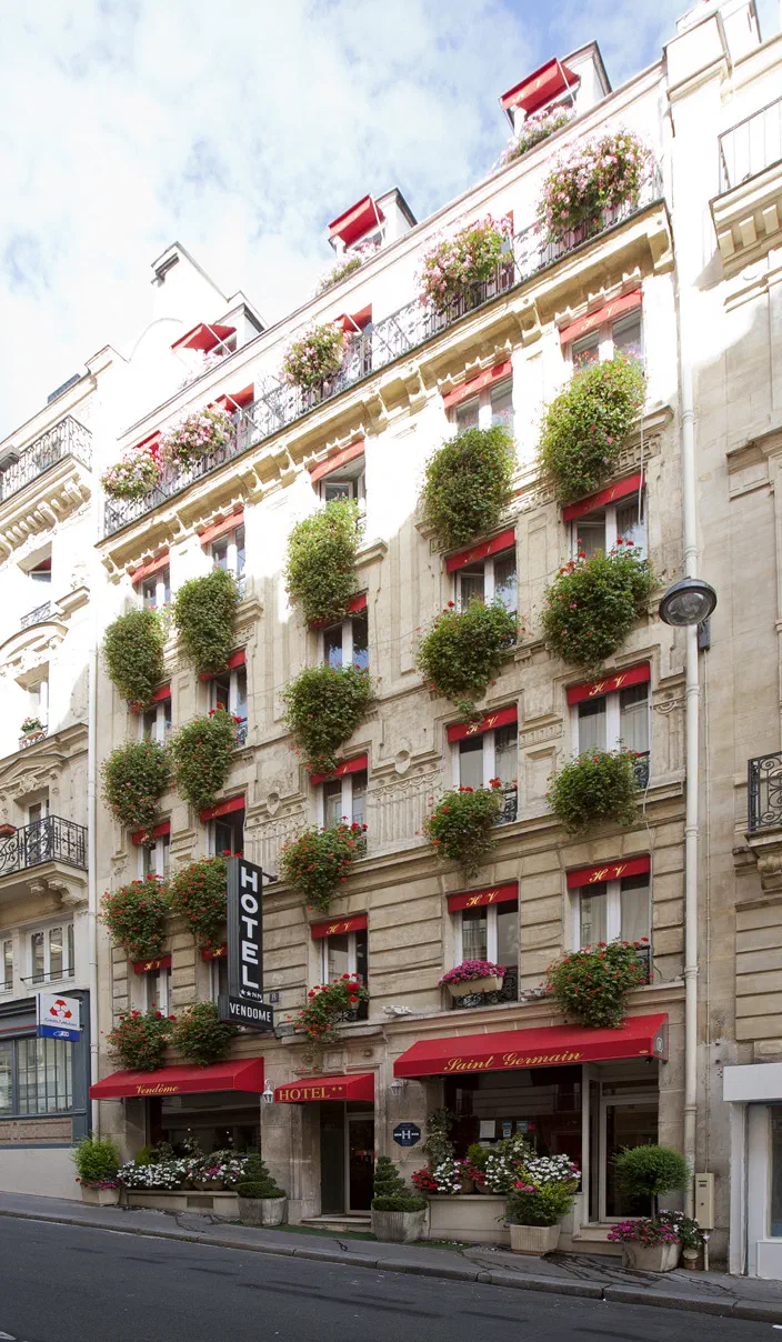 Front of the Hotel Vendôme Saint-Germain in Paris – a stone building with red awnings and flower boxes under every window