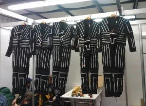 Black Tron Dance suits lined with white LED strips hanging on hangers backstage, ready for the show
