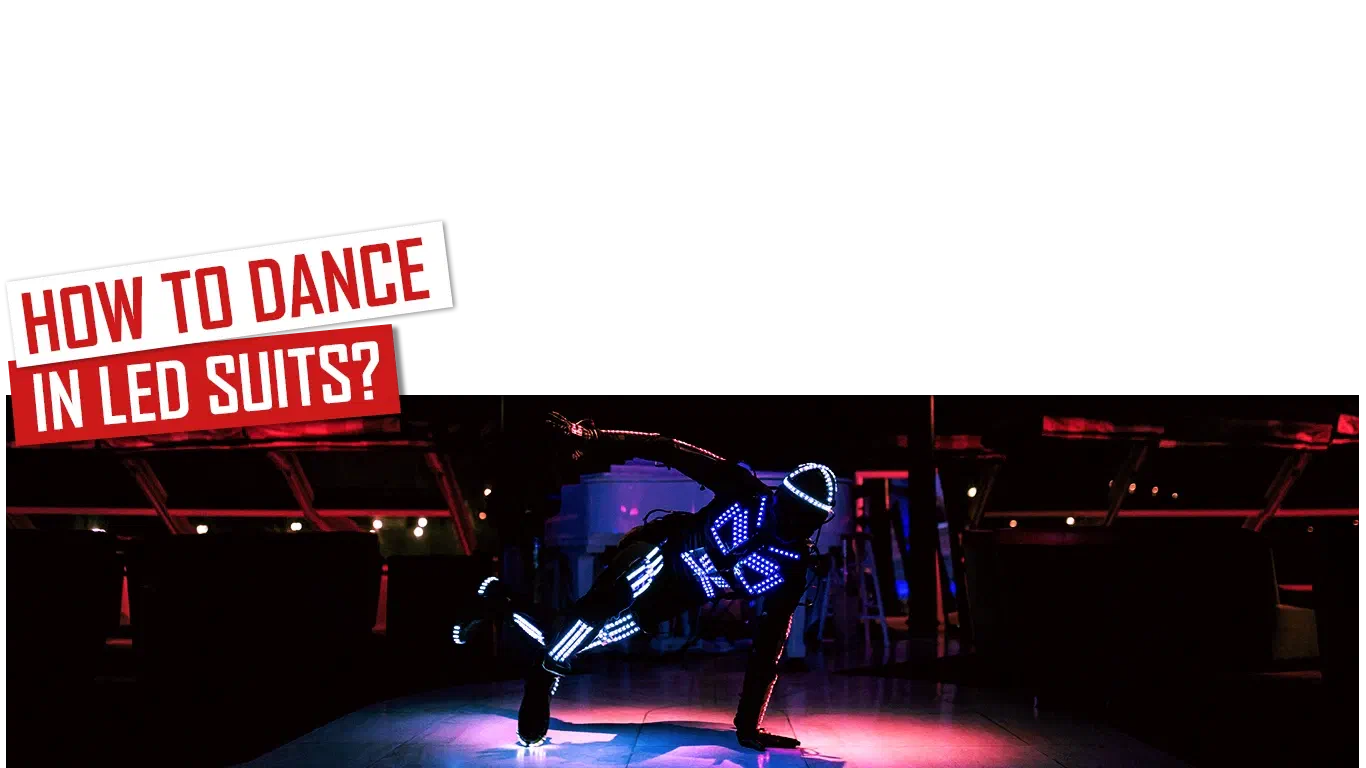 How to dance in LED suits? – red and white banner above a dancer in a glowing blue LED suit doing a one-hand floor move on a dark stage