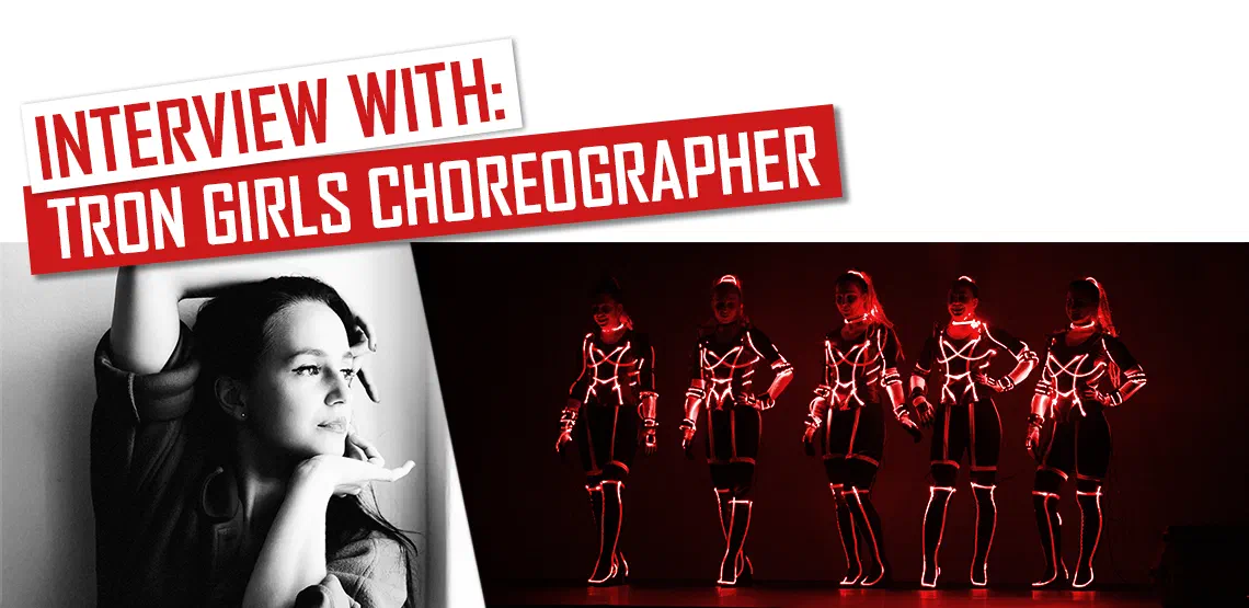 Interview with: Tron Girls choreographer – red banners above a black-and-white portrait of the choreographer and five Tron Girls in glowing red LED suits on a dark stage
