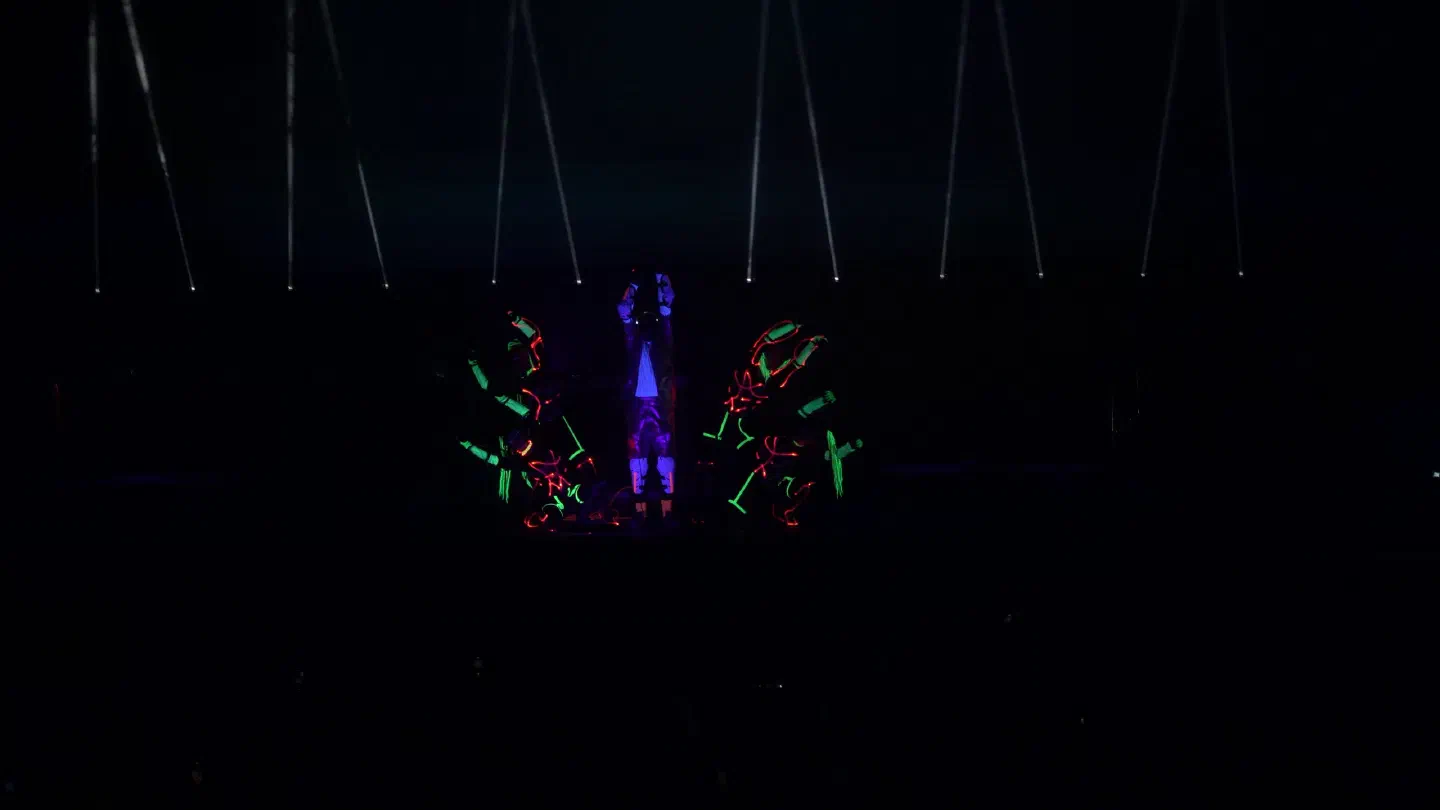 Tron Girls glowing in red and green on the dark Pohoda stage, kneeling on both sides of Fulcrum, under thin white light beams
