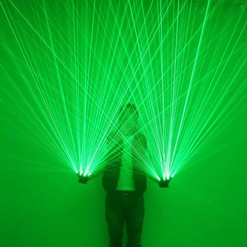 A performer in a dark room wearing laser gloves, with dozens of green laser beams fanning out from the fingers of both hands