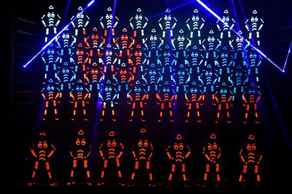 Large Tron Dance formation of LED-suited dancers in blue and orange light