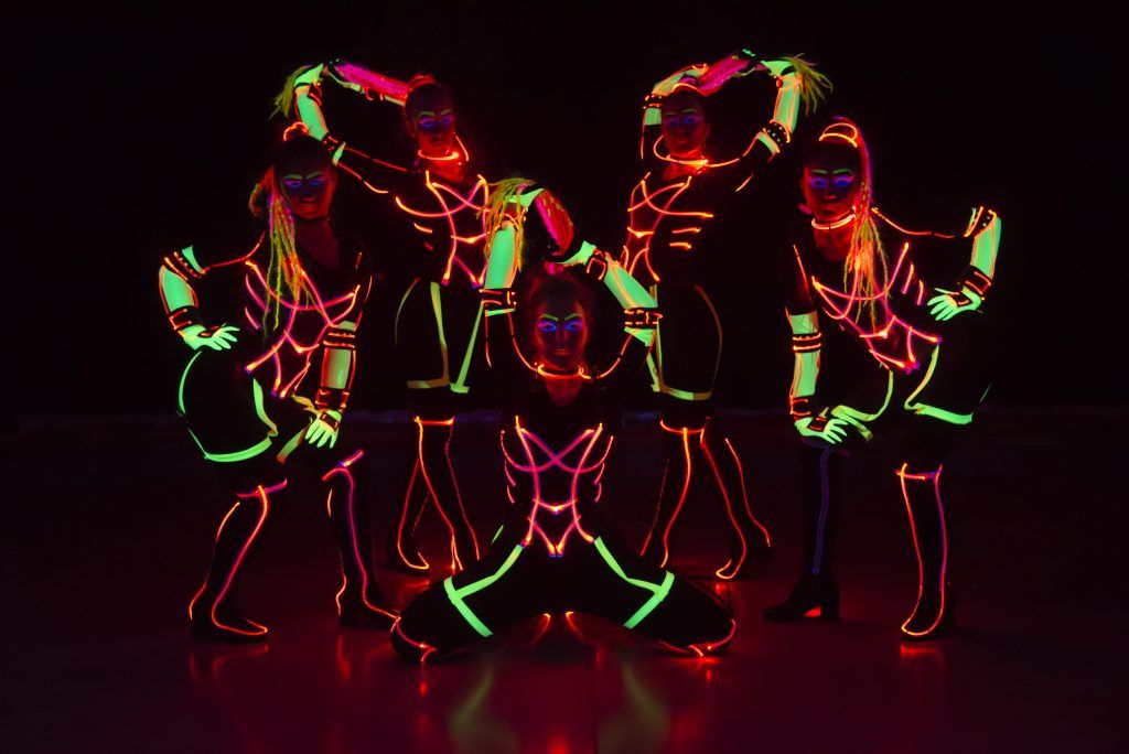 Five Tron Girls dancers posing in neon-outlined LED costumes