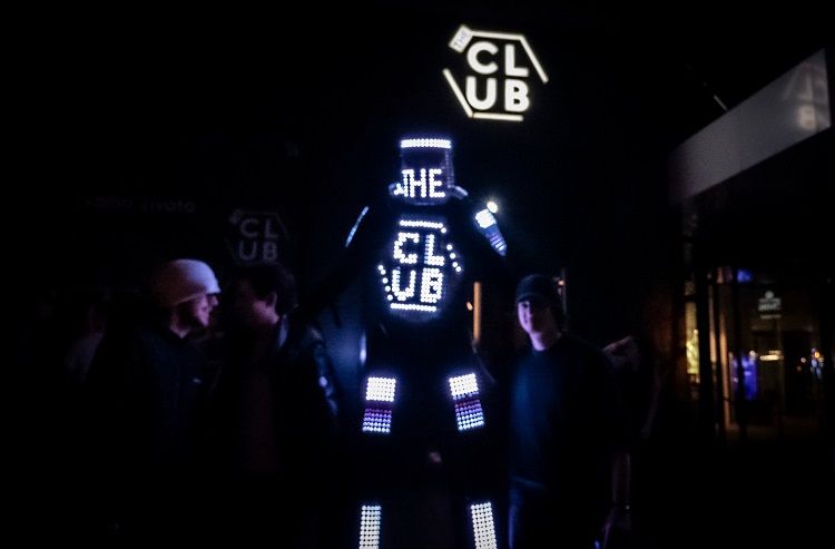 Tron Pixel Robot on stilts with a glowing LED pixel display among club guests