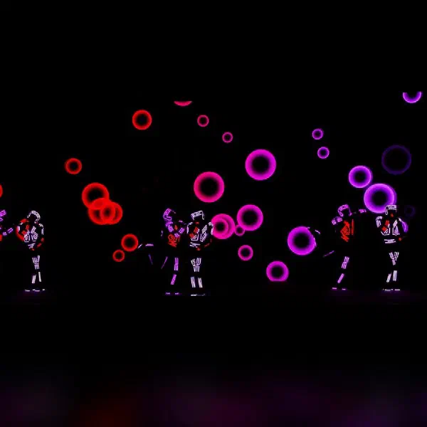 Tron Dance Gen II: LED dancers in pairs among floating red and violet rings projected on the stage screen