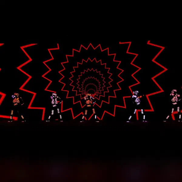 Tron Dance Gen II: seven LED dancers in front of a red zigzag spiral tunnel projected on the LED screen