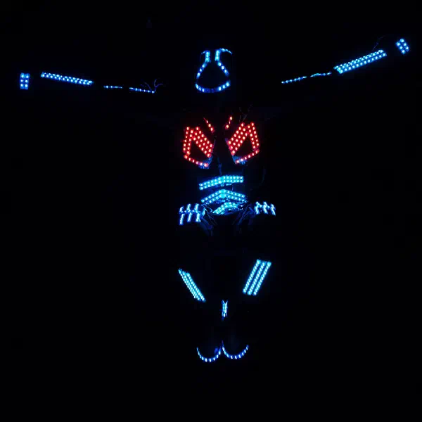 Tron Dance: solo dancer with arms outstretched in a blue LED suit with red chest lights against total darkness