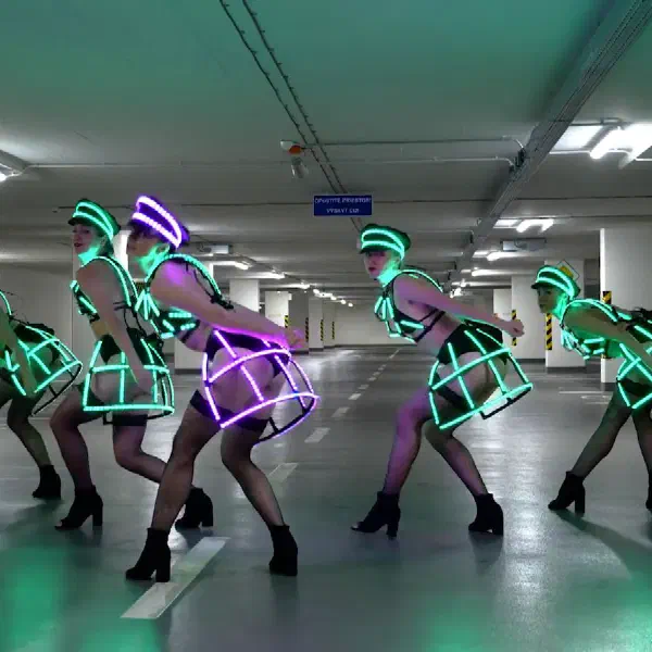 Tron Dolls: päť LED tanečníc v zelených svetelných klietkových sukniach, jedna v ružovej, v predklone v podzemnej garáži