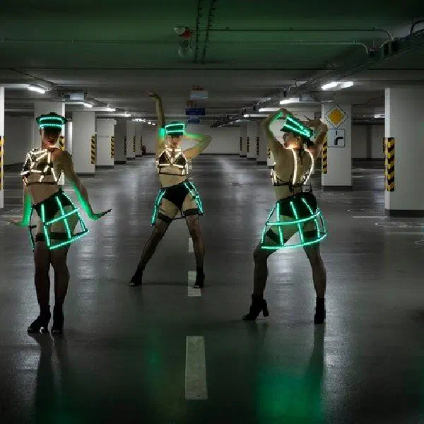 Tron Dolls: päť LED tanečníc v zelených a bielych LED klietkových sukniach pózuje v slabo osvetlenej garáži