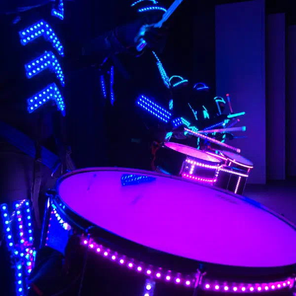 Tron Drummers: detail ružovo svietiaceho LED bubna a modrého LED kostýmu bubeníka so svietiacimi paličkami