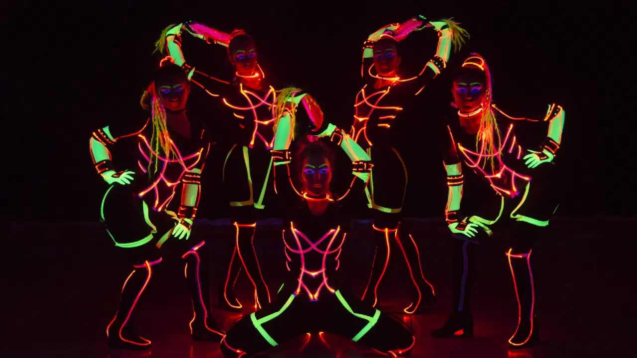 Tron Girls: five female dancers in neon green and orange LED & UV costumes posing on a dark stage