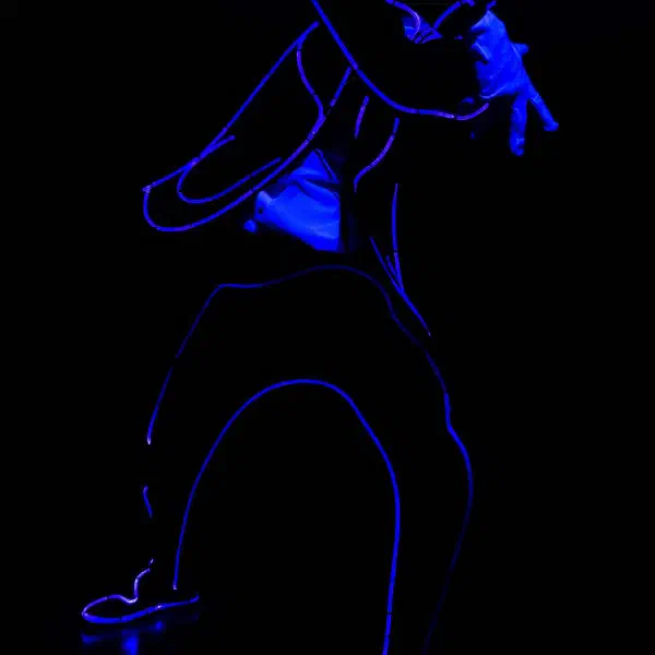 Tron Man: solo dancer outlined in blue light wire striking a crouching pose with one hand raised