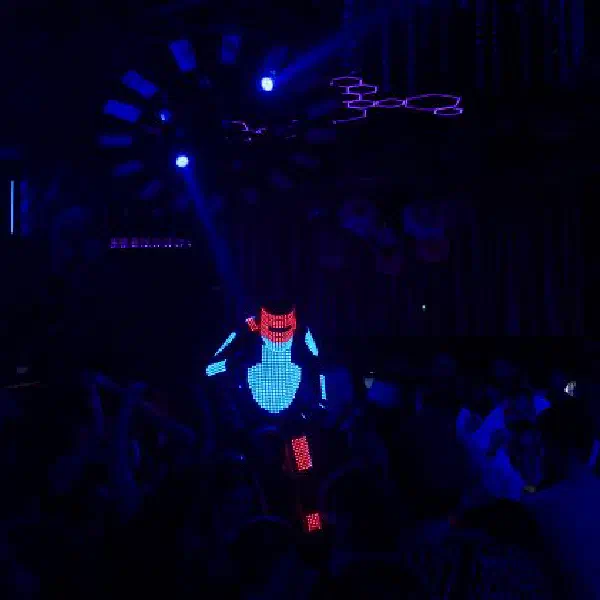 Tron Pixel Robot: LED robot stilt walker with a red helmet and blue chest towering over a club crowd