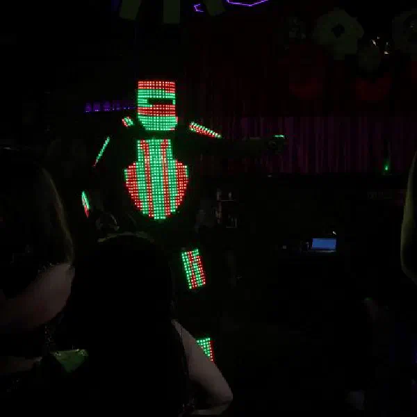 Tron Pixel Robot: LED robot in red and green pixel lights, arm outstretched, among party guests in a dark venue