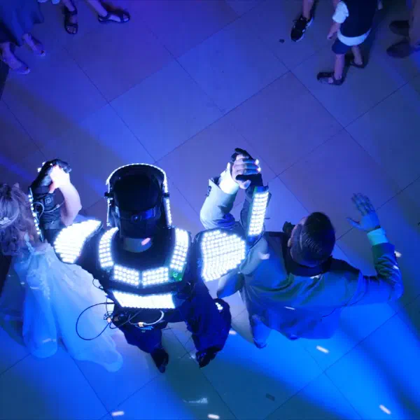 Tron Pixel Robot at a wedding: the LED robot in a glowing white suit holding hands with the bride and groom on a blue-lit dance floor