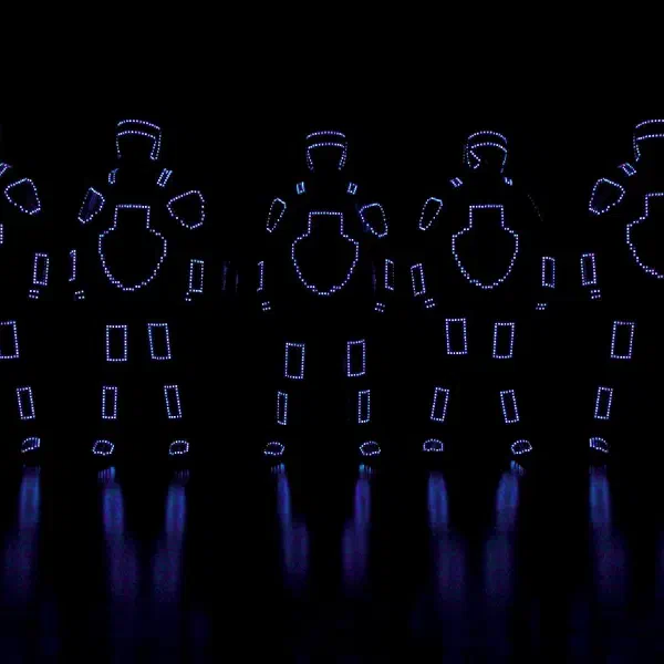 Tron Pixel Show: päť pixelových LED tanečníkov vo fialových obrysových kostýmoch v rade, odrážajúcich sa na lesklom čiernom pódiu