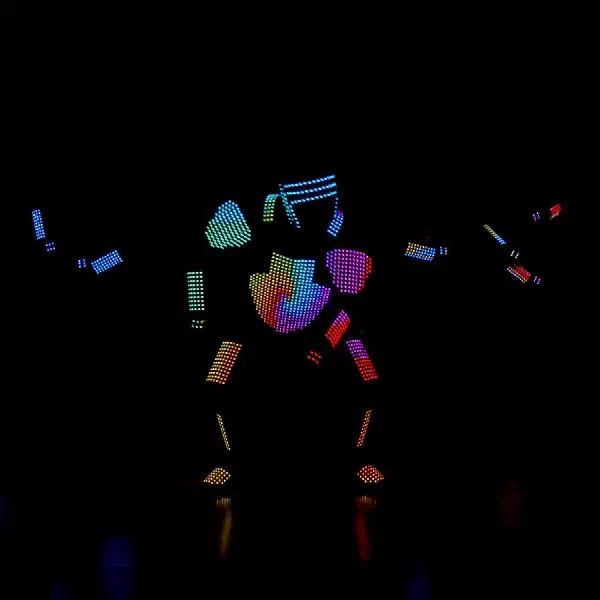 Tron Pixel Show: pixelový LED tanečník v dúhovom pixelovom kostýme uprostred pódia, v tme žiaria ruky dvoch ďalších