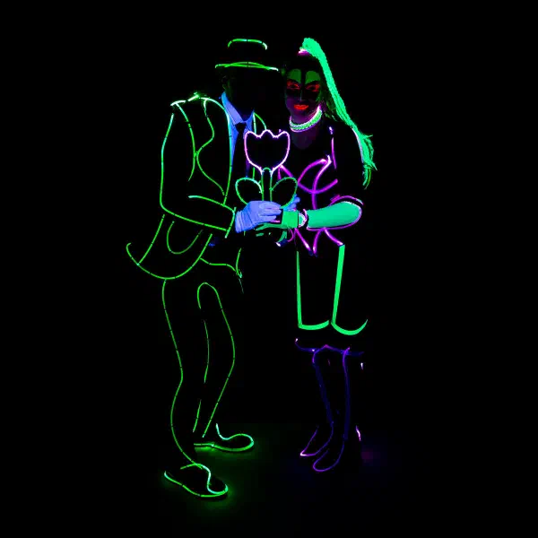 Wedding Show: couple in green and pink neon wire costumes holding a glowing tulip together in the dark