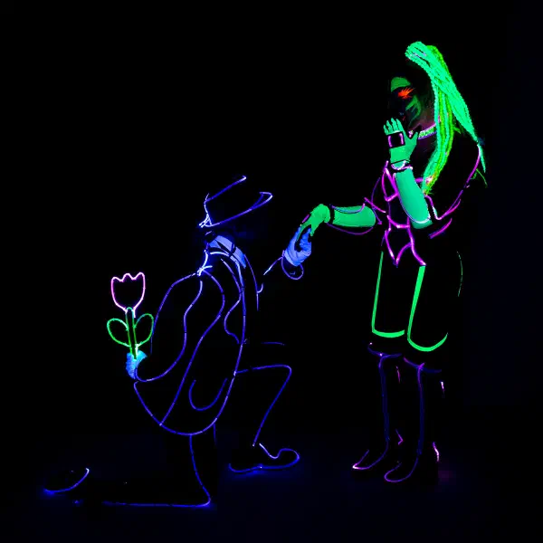 Wedding Show: man kneeling with a glowing tulip behind his back as he takes the hand of a woman in neon