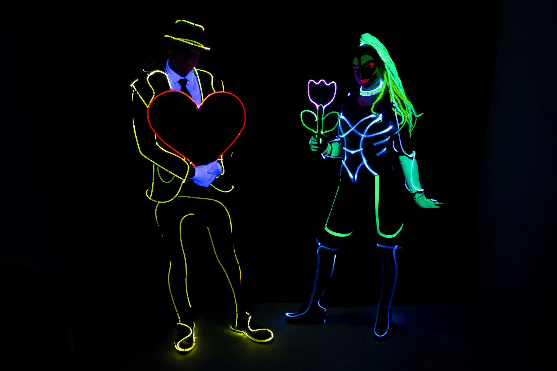 LED wedding show: two dancers in glowing outline costumes holding an LED heart and an LED flower