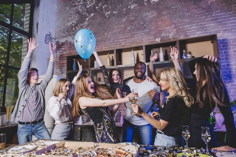 Group of young adults enjoying a lively party with friends indoors—celebrating with food, drinks, and balloons, showing how organizing a party with friends can be a great way to start with event planning
