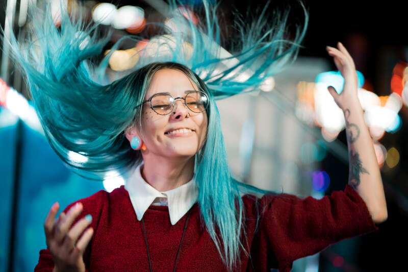 Young woman with vibrant blue hair enjoying a lively event, expressing creativity and confidence—qualities that shine in the event planning world